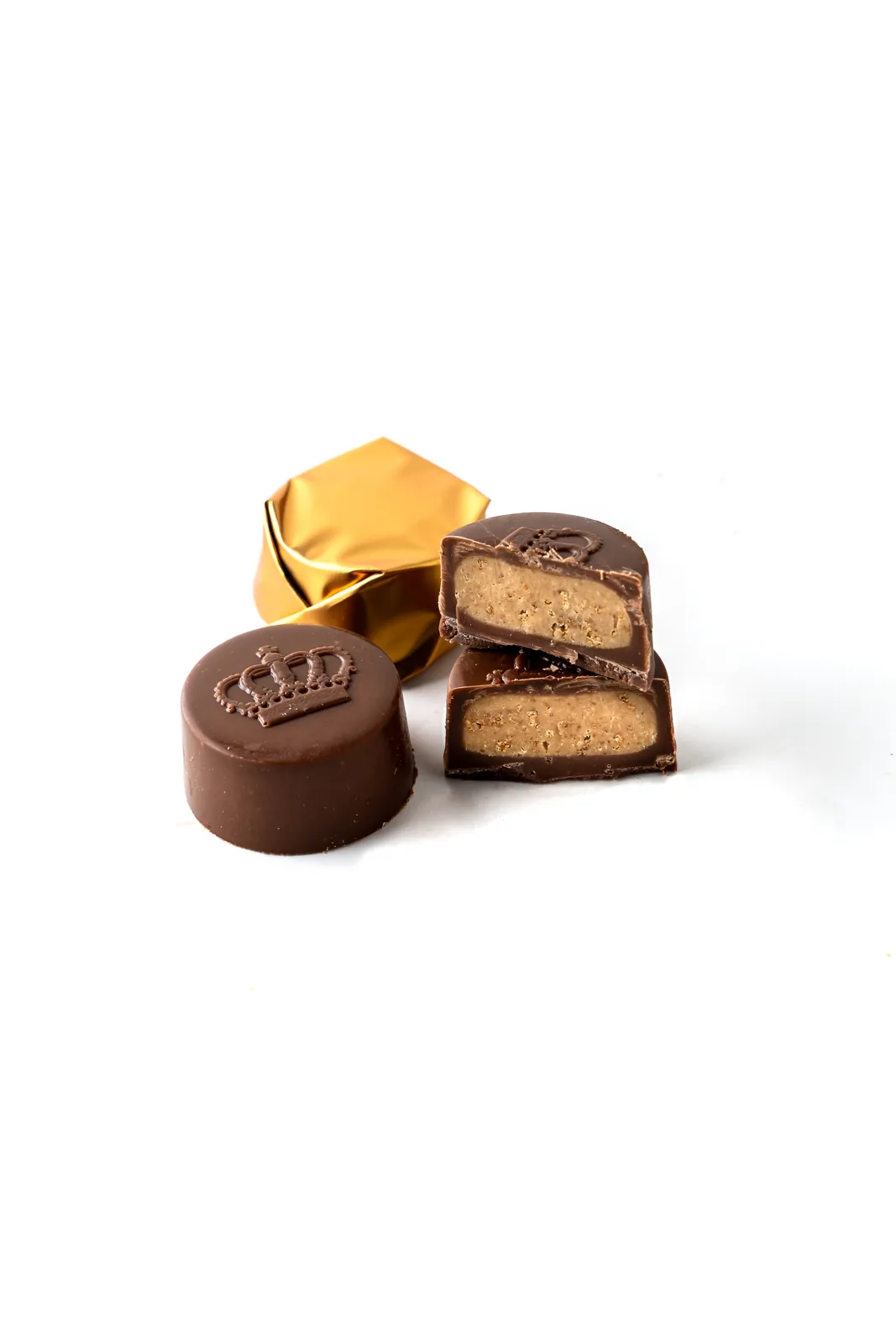 Round chocolate stamped with a crown emblem beside gold foil and praline filling