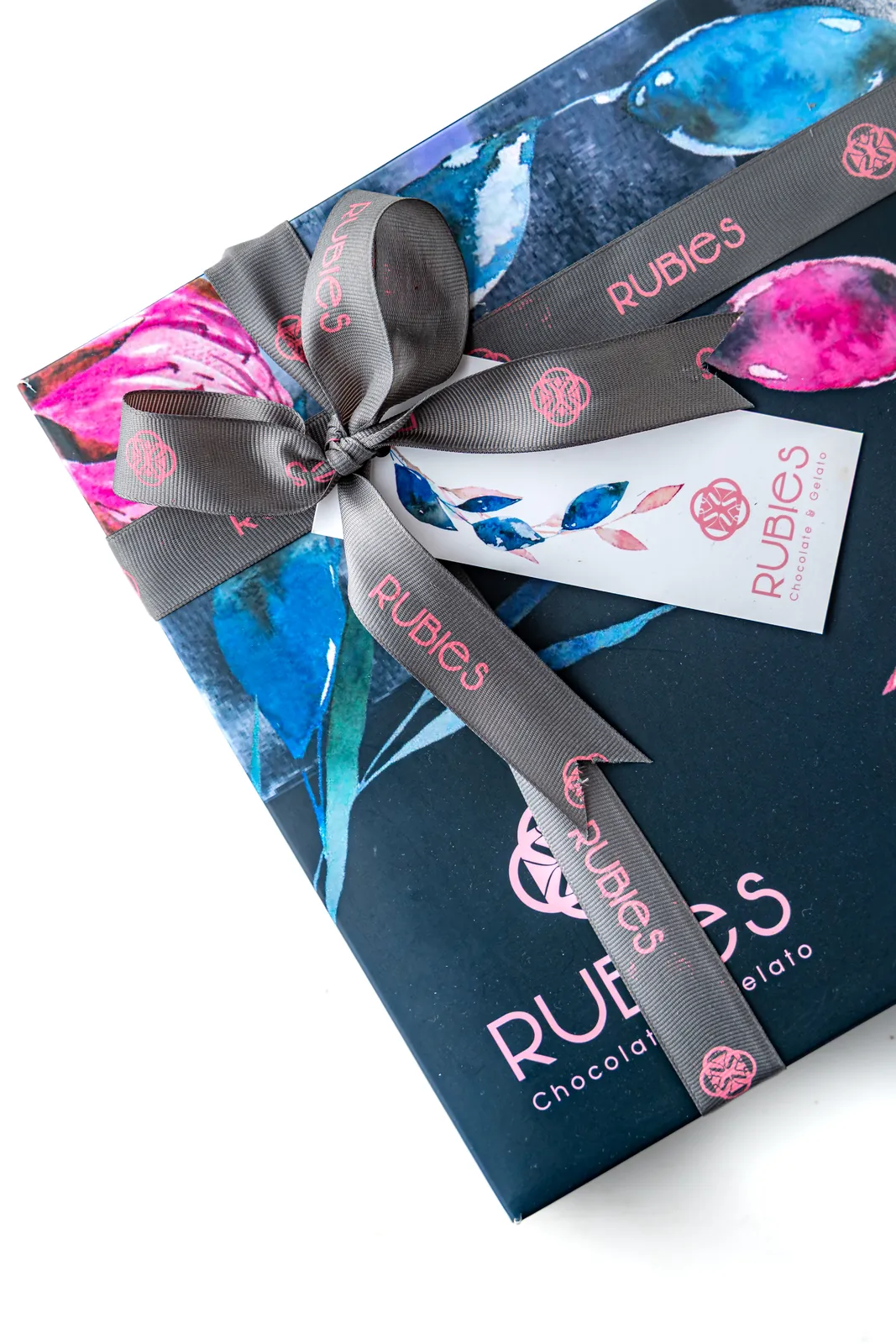 Close-up of a navy Rubies gift box with watercolor florals, branded ribbon and tag