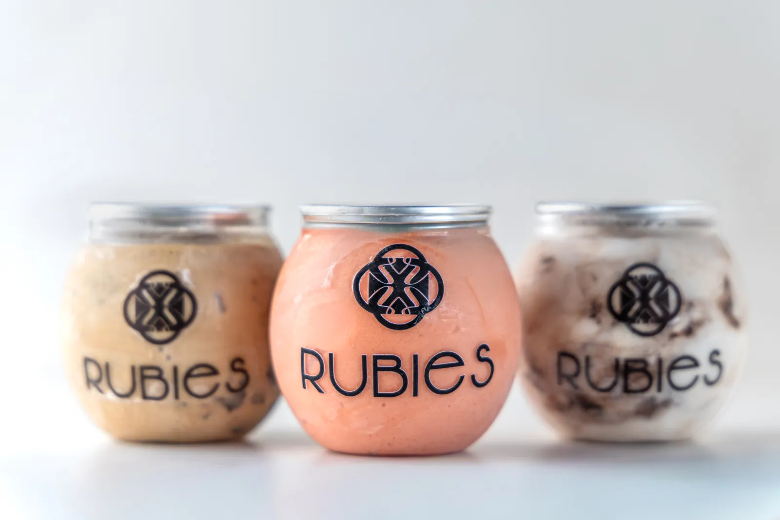 Three Rubies-branded gelato jars in different flavors on a white background