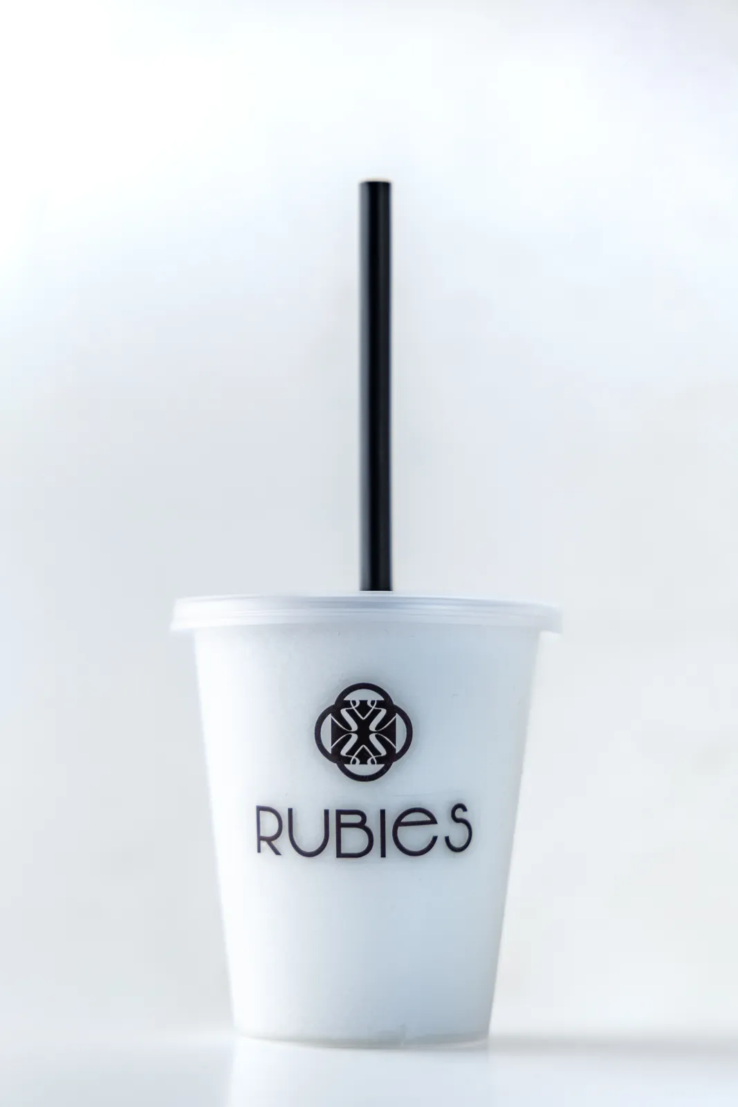 Clear Rubies cup with a pale blended frozen drink and a tall black straw